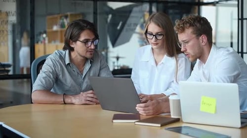 Young Adults Collaborate Around Table with Laptops