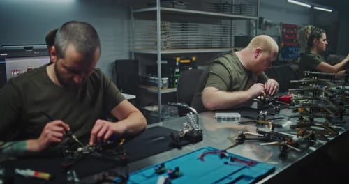 Busy Well Lit Tech Workshop Shows Multiple Engineers Immersed in Drone Development