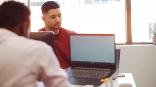 Young businessmen collaborate using laptops in a modern open plan office
