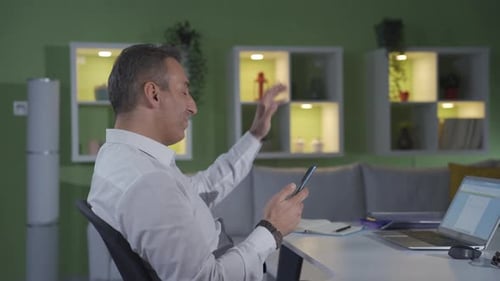 Adult Man Using Smart Phone and Typing at Desk