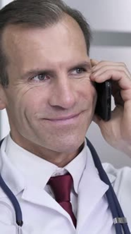 Smiling Doctor in Lab Coat Talking on Cellphone