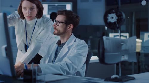 Entwicklungsingenieur für Maschinenmotoren arbeitet an seinem Schreibtisch am Computer und spricht mit Projektleiter Sh