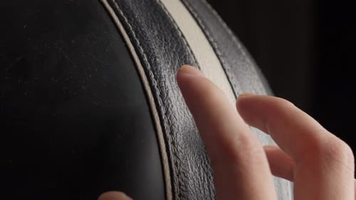 Close-up of a hand running fingers over textured black leather, emphasizing touch and detail
