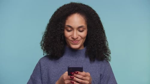 Smiling Woman Using Smartphone on Blue Background