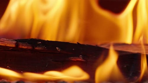 Eine Nahaufnahme von Holz, das in einem offenen Feuer brennt Eine helle Feuerflamme verbrennt Holz zum Grillen im Freien