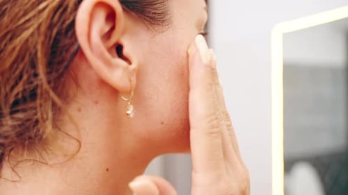 Woman Applying Lotion to Face in Close Up