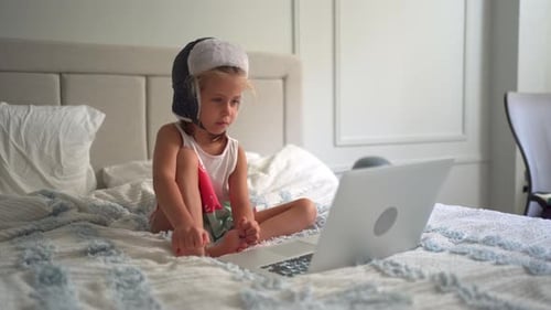 Child Watching Laptop in Bedroom With a Hat