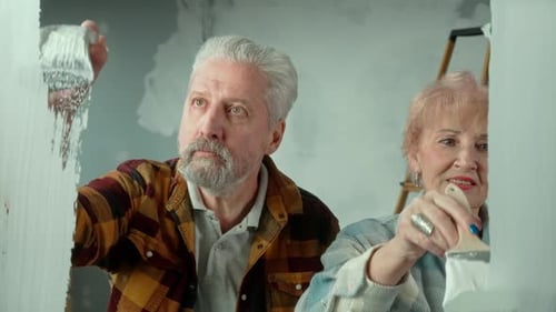 Loving Elderly Couple Painting Wall Together at Home