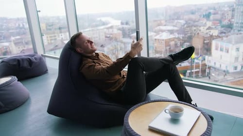 Man Using Mobile Phone Relaxing in Modern Office