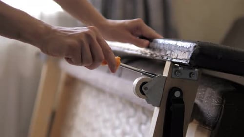 Hands Using Screwdriver on Furniture Frame