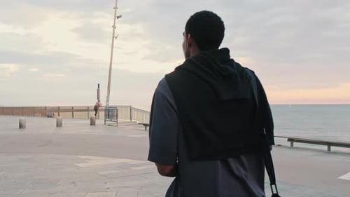 Young Man Walking on Beach at Sunset