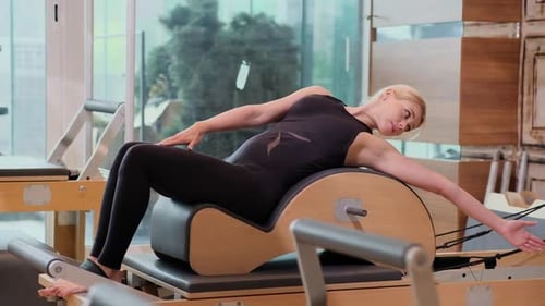 Professional Pilates Training in Modern Gym Blonde Woman Stretching and Relaxing Body on Reformer