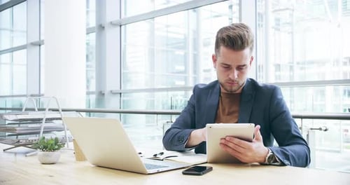 4k video footage of a handsome young businessman using a digital tablet in the office