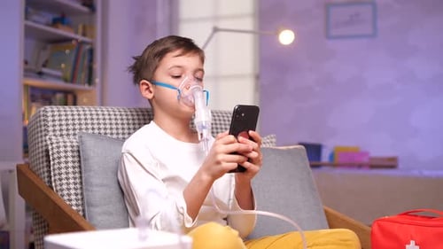 Boy Uses Nebulizer While Looking at Cellphone