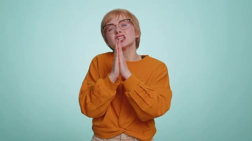 Woman Clasping Hands Together Against Pale Blue Backdrop