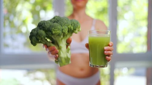 Woman Holding Broccoli and Green Juice for Health