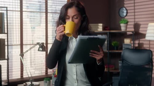 Young Adult Woman Drinking Coffee Holding Folder