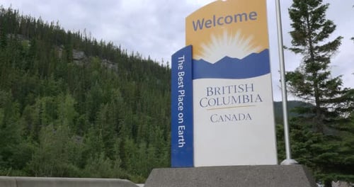 Welcome sign to British Columbia, Canada surrounded by lush green forest
