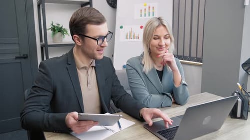 Office Colleagues Discussing Data on Laptop and Tablet