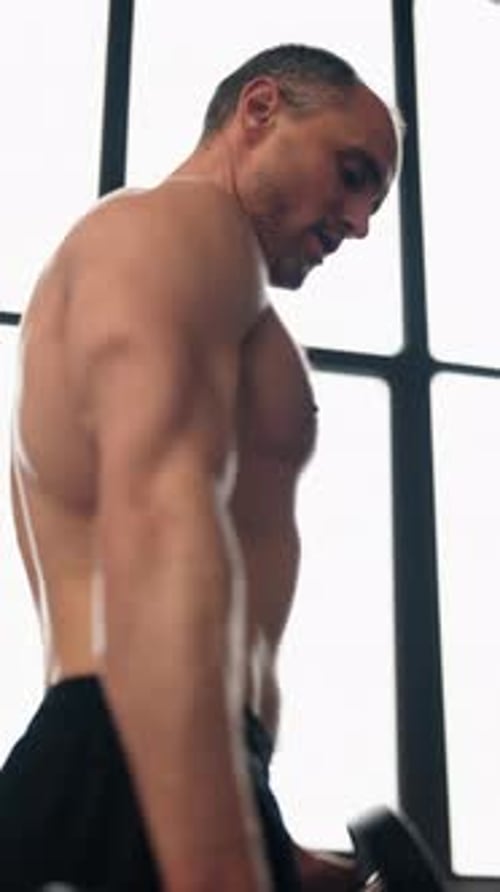 Muscular Athlete Exercising Lifting a Heavy Dumbbell