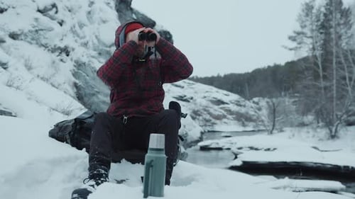 Man with Binoculars Relaxing in Snowy Winter Landscape