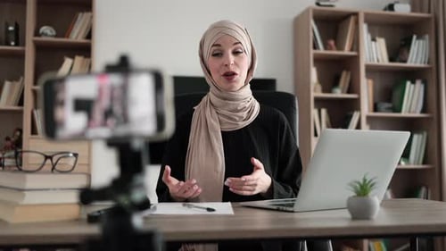 Charming Muslim Woman in Hijab Talking and Gesturing While Recording Video on Modern Phone