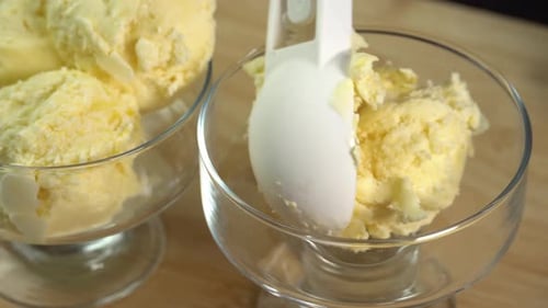 Homemade ice cream prepared at home, hand placing scoops of ice cream in dessert bowl