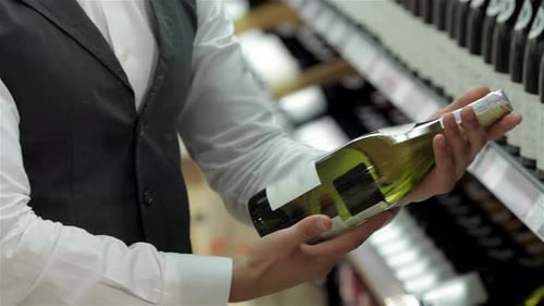 Man Examining Wine Bottle in Retail Setting