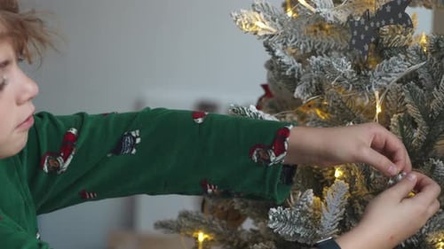 Child Decorating Christmas Tree with Silver Bauble