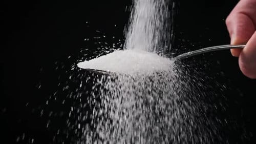Sugar Falls Into Spoon on Black Background Slow Motion CloseUp Copy Space