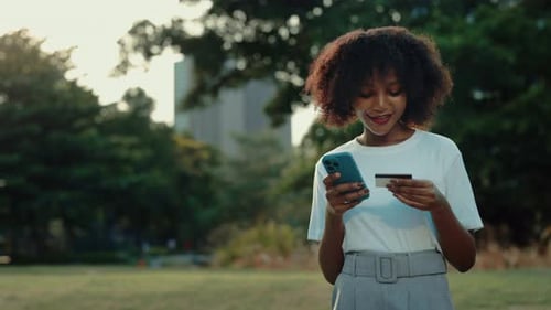 Portrait of Happy African American Woman Using Online Banking App in Green Park