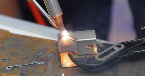 Laser welding machine with hand hold gun. Laser welding is shown in close-up.