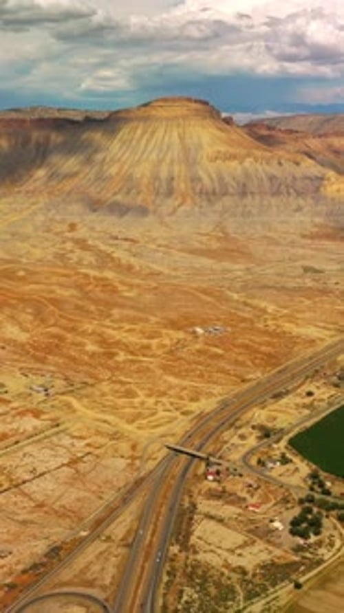 Des autoroutes séparent une terre déserte de sable sec d'une belle ville oasis au pied de la montagne.