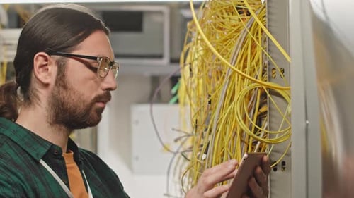 Man Using Smartphone Next to Server Rack