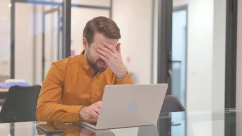 Man Frustrated While Working on Laptop in Office
