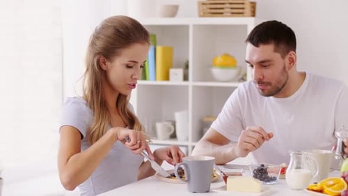 Couple Eating Breakfast and Drinking Coffee at Table