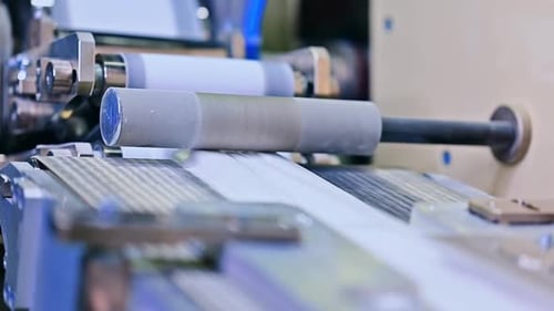 Paper Moving Through Industrial Manufacturing Machine Close Up