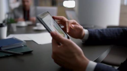 Financial analyst hands on tablet researching charts in modern office building