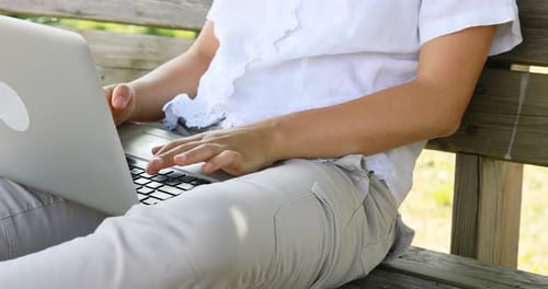 Woman Using Laptop on a Park Bench
