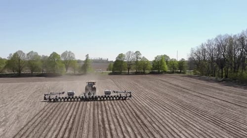 Großer gelber Traktor, der Mais in der Ukraine pflanzt. Traktor arbeitet auf dem Feld