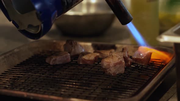 Grilling Meat With A Flame Gun Torch In A Restaurant Kitchen. - closeup ...