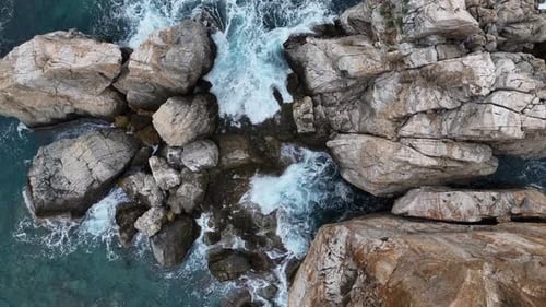 Dramatisch Farbe der Meereswellen, die gegen die Felsen prallen, Luftbild an einem wilden Strand