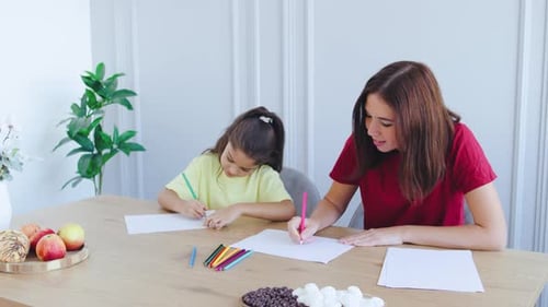 Woman and Child Drawing Together Indoors at Table