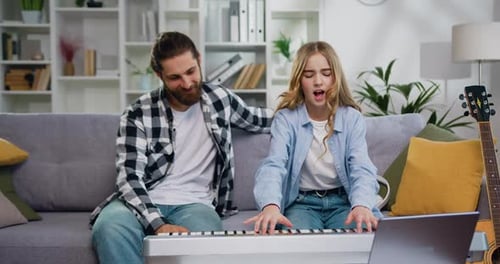 Encantadora hija toca el piano con su padre en la sala de estar con un momento feliz. Niño aprendiendo jugando