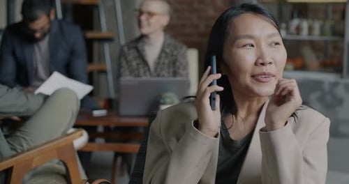 Successful Asian Businesswoman Talking on Mobile Phone Working From Creative Modern Office