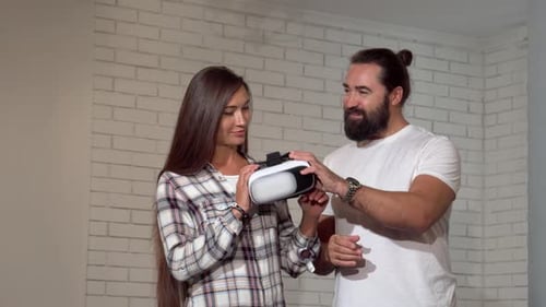 Man Shows Woman a VR Headset Indoors