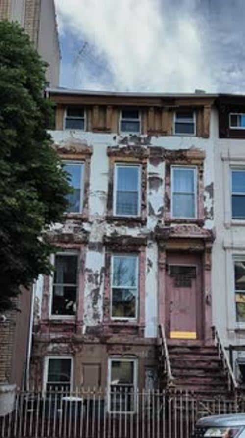 Weathered Brownstone with Peeling Paint on Residential Street in Brooklyn, NYC