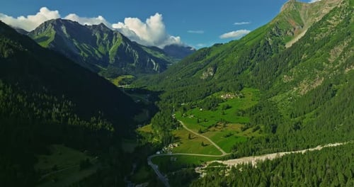 Drone survole une vallée pittoresque verdoyante avec des montagnes en arrière-plan de hautes montagnes célèbres