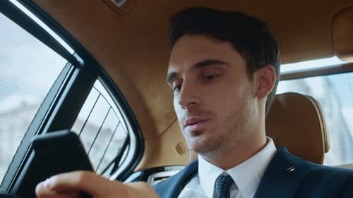 Focused young adult using phone in car interior