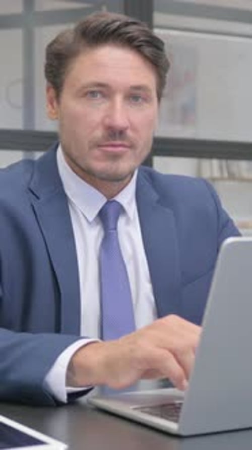 Thumbs Up by Businessman Looking at Camera in Office